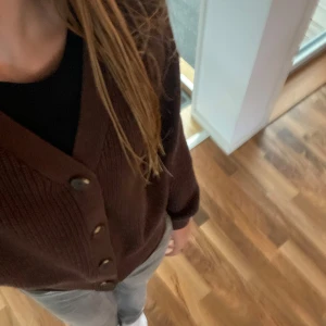 Brun stickad kofta från H&M💌 - Mysig brun kofta från H&M med ribbstickat material och stora knappar framtill. Koftan har v-ringning, lång ärm och en croppad passform som ger en trendig look. Perfekt att slänga över en t-shirt eller linne för extra värme.🤍💌💋