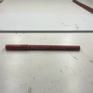 PINK KEY matt läppenna rosabrun - Matt läppenna från PINK KEY i en snygg rosabrun nyans. Pennan har klassisk träkropp och är lätt att vässa för en skarp kontur. Perfekt för att definiera läpparna eller fylla i hela läppen för en matt finish.