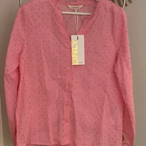  blus!  - Perfekta sommarplagget! Säljer en söt rosa blus från ONLY med broderade detaljer och knappar framtill. Blusen har långa ärmar och ett diskret prickigt mönster. Perfekt för en fräsch och stilren look.     