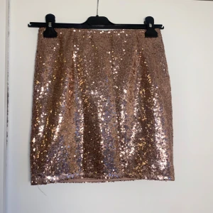 Glittrig guld minikjol från Esmara - Supersnygg kortkjol från Esmara i storlek 34. Kjolen har rak passform, elastisk midja och är helfodrad för extra komfort. 