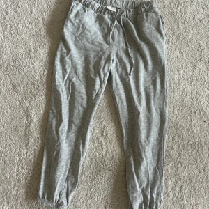 Grå mjukisbyxor med snörning  - Säljer ett par grå mjukisbyxor med elastisk midja och snörning. Byxorna har resår vid bensluten,sköna och passar perfekt för chill dagar.