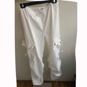 Vita cargopants   - Säljer ett par vita cargopants med elastisk midja och snörning. Byxorna har stora fickor på sidorna. Dom är S men passar M oxå. Tycker dom är jätte fina, men dom är väldigt pösiga så inte använt dom tycker inte dom är fina påig MEN många personer är sååå så så såååå snygga i de💕 materialet är tyg men kan kännas lite plastig typ oxå men sköna luftiga ändå, Jag är 169 ca cm lång och dom passar bra på längden när jag sätter dom low waist annars lite korta.🫶🏼