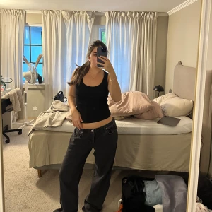 Svarta loose fit jeans NA-KD  - Säljer ett par svarta jeans med loose fit och låg midja. Byxorna har klassisk femficksdesign och raka, vida ben. Perfekta för en avslappnad och trendig look. Passar dig som gillar baggy stil och vill ha bekväma jeans med streetkänsla.