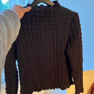 Brun långärmad topp från Wera - Säljer en brun långärmad topp från Wera i storlek S. Tröjan har ett unikt rutigt strukturmönster och en lätt vågig kant vid halsen. 