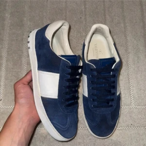 Valetino flycrews - Snygga sneakers från Valentino Garavani i blå mocka med vita skinnpaneler och coola nitar på hälen. Skorna har rund tå, platt sula och klassisk snörning. Perfekta för dig som vill sticka ut med exklusiva detaljer och stilren design. 