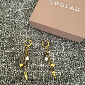 Guldiga örhängen från Edblad - Så himla fina guldiga örhängen från Edblad med hängande kedjor, hjärtformad detalj, glittrande sten och spetsig kon längst ner. Har tyvärr inte kommit till användning. 