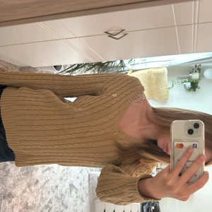 Brun kabelstickad tröja Lauren Ralph Lauren - Kabelstickad beige tröja från Lauren Ralph Lauren med v-ringning och diskret RL-logo på bröstet. Säljer då den inte kommer till användning. Perfekt för höst och vinter 💗Ingen tecken på användning.