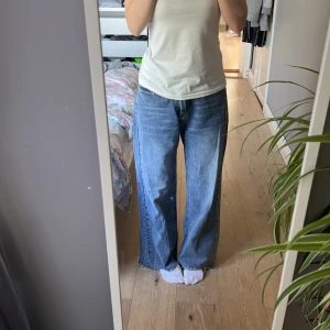 Wide jeans från Dazy i blå denim - Säljer ett par blå jeans från Dazy i storlek L. De har en loose och wide passform med råa, fransiga benslut och klassisk femficksdesign. Jeansen är tillverkade i denim och har en avslappnad vibe, perfekta för en chill och trendig look.
