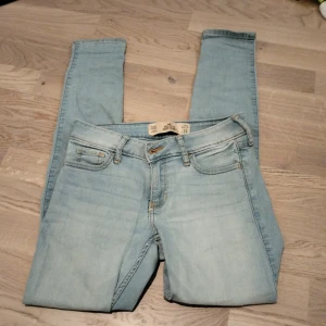 Ljusblå super skinny jeans Hollister - Säljer ett par ljusblå super skinny jeans från Hollister. Modellen har klassisk femficksdesign, snygga kontrastsömmar och läderpatch med logga bak. Jeansen är stretchiga och sitter tight hela vägen ner.