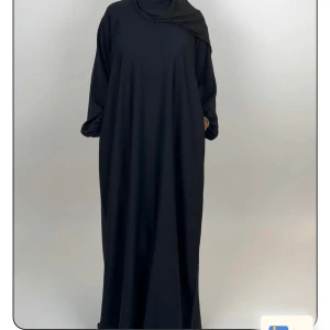 Svart abaya med lång ärm - Snygg svart abaya med lös passform och stängda ärmar. Klänningen har en enkel och stilren design utan mönster, perfekt för dig som gillar minimalistiskt mode. Tillverkad i ett mjukt och lätt material som faller fint. Från luude collection