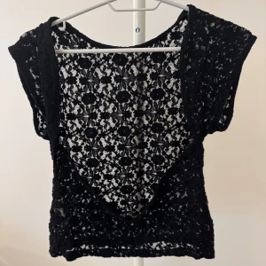 Svart spetsblus från Stradivarius - Svart blus från Stradivarius i storlek M, helt i genombruten spets med blommigt mönster. Modellen är ärmlös med rund halsringning och har en lätt loose passform. Använt ett få tal gånger 🩷