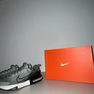 Nike Air Max grå sneakers - Snygga Nike Air Max sneakers i grått med svart swoosh och vit sula. Ovandelen är i mesh för bra andningsförmåga och skon har en tydlig Air Max-dämpning i hälen. Perfekta för dig som gillar sportig och modern stil.
