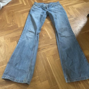 Ljusblå bootcut jeans med låg midja - Säljer ett par ljusblå jeans med bootcut-modell och låg midja. Jeansen har klassiska fickor fram och bak,  och stängs med dragkedja och knapp. Innerbenslängden:84cm, midjemått: 38cm