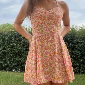 Blommig kort klänning med smala axelband🩷 - 🩷Supersöt kort klänning med blommigt mönster i rosa, orange, gul och grön. 🩷 Klänningen har smala axelband, v-ringning och öppen rygg. 🩷 Klänningen är från Bianca Ingrossos egna kollektion för Gina Tricot som hon gjorde för ett fåtal år sen.  🩷Säljer pga är för kort för min smak. 🩷Tvättas såklart innan den postas. 🩷Endast använd 2 ggr. 🩷Strl S men passar även XS enligt mig.  🩷Priset kan diskuteras.