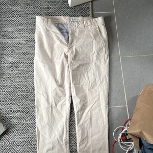 Beige chinos från Boomerang W32 L34 - Snygga beige chinos från Boomerang med klassisk rak passform. Byxorna har bälteshällor, två fickor fram och två bakfickor. Tillverkade i mjuk bomull, perfekta för en clean och stilren look.