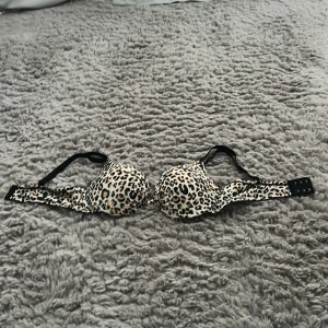 Leopardmönstrad push-up bh/bikini - Snygg bh med leopardmönster i svart, beige och brunt. Kuporna är vadderade och har en liten twist-detalj framtill. Axelbanden är svarta och justerbara. Perfekt som bikini.