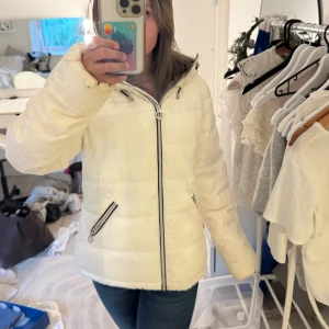 Vit vinterjacka från Röhnisch - Snygg vit jacka från Röhnisch med luva och svarta detaljer. Jackan har dragkedja framtill och två fickor med dragkedjor. Perfekt för kalla dagar och riktigt skön att bära. Klassisk, stilren look som funkar till allt. Det är en väldigt tjock jacka så själv har har använt den under kalla vinterdagar och i skidbacken. Storleks lappen har tyvärr åkt av men den passar mig som vanligtvis har xs/s i kläder. Men skulle säga att den är ”stor” i storleken.