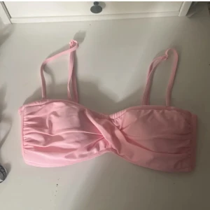 Ljusrosa bikiniöverdel  - Supersöt ljusrosa bikiniöverdel från Stadium i bandeau-modell med twistad front och justerbara axelband. Tillverkad i mjukt syntetmaterial som torkar snabbt. Perfekt för strandhäng och pooldagar!