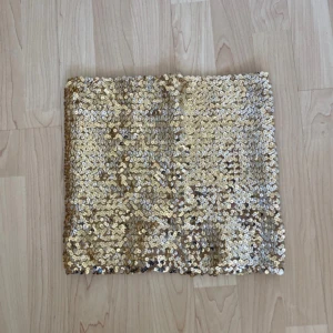 Guldig paljett-tubtopp - Glittrig tubtopp i guld med massor av paljetter som fångar ljuset. Perfekt för dig som vill sticka ut och glänsa. Axelbandslös bandeau-modell som sitter snyggt och bekvämt.