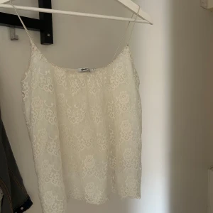 Vit spetsig linnetopp  - Säljer en söt vit linnetopp från Gina Tricot med tunna axelband och vacker spets över hela toppen. Perfekt för varma dagar. Enkel och romantisk look som passar till mycket.