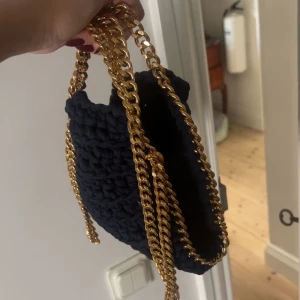  Handgjord handväska med guldkedja - Säljer en blå stickad / virkad handgjord handväska med chunky guldfärgad kedja som axelrem. Väskan har en mjuk, virkad look. Jag köpte den av en person som tillverkar de för hand, köpa för 700kr säljer för 250 ❤️