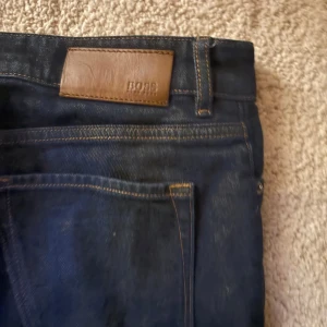 Mörkblå jeans från BOSS - Snygga mörkblå jeans från BOSS med klassisk femficksdesign och bruna kontrastsömmar.👍