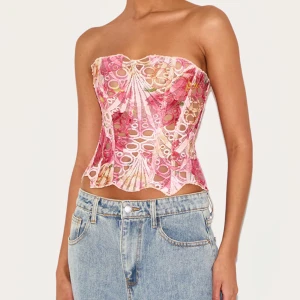 Rosa blommig korsett topp med snöring - Säljer denna super fina och populära korsett topp från Pretty Little Thing, i gott skick och endast använd en gång, säljer då den var lite liten på mig vilket är synd eftersom att den är så fin, storlek 10 vilket motsvarar storlek 38 eller M <3