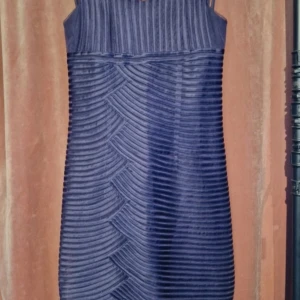 Mörklila kortklänning från Phase Eight - Snygg mörklila kortklänning från Phase Eight med coola ribbade detaljer och unika smala axelband. Klänningen har ett strukturerat mönster och är tillverkad i polyester, bomull och elastan för en bekväm passform. Perfekt för dig som vill sticka ut med stil.