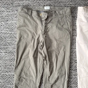 Beiga chinos från Boomerang W32 L34 - Snygga beiga chinos från Boomerang i klassisk rak modell. Byxorna har bälteshällor, knapp- och dragkedjestängning samt två bakfickor. Tillverkade i bomull för en skön och avslappnad känsla. Perfekta för en clean och stilren look.