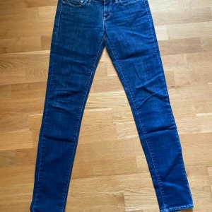 Levi's skinny jeans blå denim - Snygga blå skinny jeans från Levi's i modellen Slight Curve. Klassisk femficksdesign, normalhög midja och smal passform hela vägen ner. Jeansen är i stretchig denim med tydliga sömmar och Levi's ikoniska bakfickor.