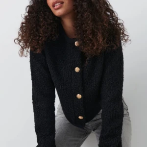 Svart kofta med guldknappar - Snygg svart jacka från Gina Tricot med guldknappar framtill. Jackan har en normal passform och är långärmad, perfekt för höst och vår. Koftan är i fint skick och är knappt använd. 