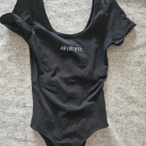 Svart body från Minga London  - Svart body med texten ''Princess'' från Minga London. Sparsamt använd, fint skick.