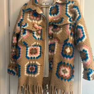 Cool vår jacka från  Front Street - Säljer en unik och färgglad kappa från Front Street med ett iögonfallande mönster i beige, blått, rosa och brunt. Kappan har långa ärmar och knappar framtill samt fransar vid nederkanten. Perfekt för att liva upp garderoben! Perfekt för våren ❤️