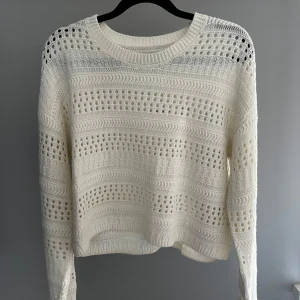 Vit stickad tröja från Pigalle - Säljer en snygg vit stickad tröja från Pigalle. Tröjan har ett unikt hålmönster och långa ärmar. Perfekt för lager-på-lager-stil och ger en luftig känsla. Passar bra till både jeans och kjol. 