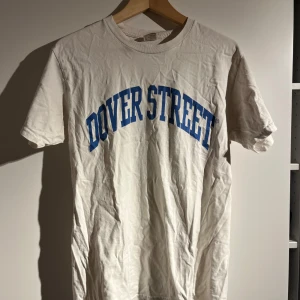 Vit t-shirt från better days  - Säljer en vit t-shirt från Better Gift Shop med blå text 'Dover Street' på framsidan. Tillverkad i 100% bomull och tryckt i Nordamerika. Nypris var 950 kr