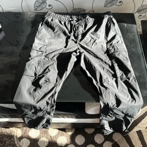 Svarta cargobyxor från H&M - Säljer ett par svarta cargobyxor från H&M i slim fit. Byxorna har flera praktiska fickor och elastisk midja för extra komfort. Perfekta för en avslappnad stil.