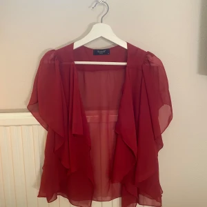 Röd transparent blus från Sisters Point - Snygg röd transparent blus från Sisters Point med korta ärmar. Blusen har en luftig design.