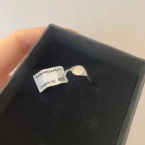 Silverring med svart sten - Elegant silverring med en rund svart sten i mitten. Ringen har en stilren design och är tillverkad i 925 silver. Perfekt för att ge en touch av elegans till din stil. Med prislapp kvar, aldrig använd!