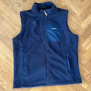 Mörkblå fleeceväst från Patagonia - Säljer en mörkblå fleeceväst från Patagonia med dragkedja och en praktisk bröstficka. Den är både stilren och funktionell. Använd några gånger, bra skick. Hör av dig vid frågor eller fler bilder 🙌