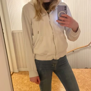 Vit hoodie med dragkedja - Säljer en stilren vit hoodie med dragkedja och fickor framtill. Perfekt för en avslappnad look. Den har långa ärmar och en bekväm huva. 💕