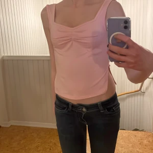 Rosa ärmlös topp - Säljer en söt rosa ärmlös linnetopp med en lätt rynkad detalj framtill. Perfekt för varma dagar och kan enkelt matchas med jeans eller kjol. Toppen har en enkel och stilren design.