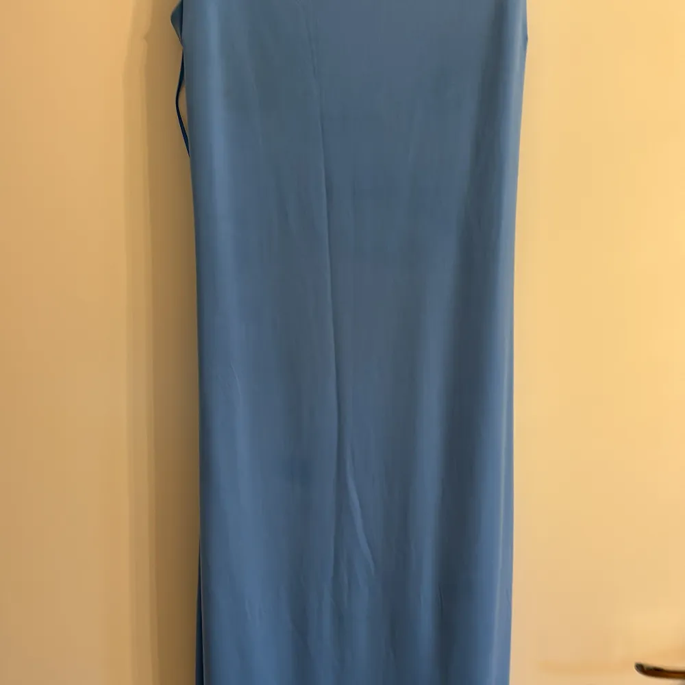 Säljer en stilren blå långklänning från Bik Bok. Klänningen har smala axelband och en enkel design som gör den perfekt för olika tillfällen. Materialet känns mjukt och bekvämt mot huden. Perfekt för dig som vill ha en elegant och minimalistisk look.. Mekot.