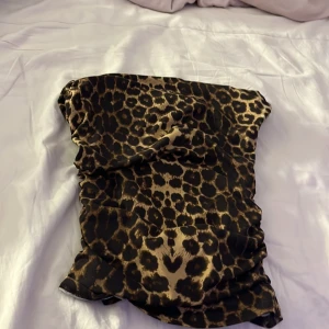 Leopardmönstrad tubtopp - Säljer en snygg leopardmönstrad tubtopp i stretchigt material. Perfekt för att ge en djärv touch till din outfit. Toppen har en tight passform och är ärmlös, vilket gör den idealisk för varmare dagar eller en utekväll.