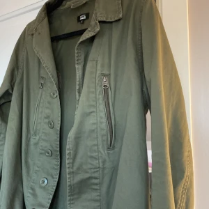 Olivgrön jacka med dragkedja och knappar - Snygg olivgrön jacka från bikbok och knappar framtill. Jackan har långa ärmar och en klassisk krage. Perfekt för en stilren look.