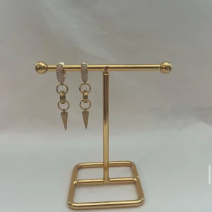 Guldiga örhängen med kedjor och spikes - Snygga guldiga örhängen med små glittrande stenar på ringen och coola kedjor som avslutas med spetsiga spikes. Perfekta för dig som vill sticka ut med en edgy vibe och ändå ha lite bling. Passar till alla outfits när du vill ha något extra.