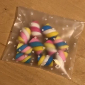 Färgglada marshmallows berlocker  - Säljer ett pack med 10 st söta marshmallows berlocker, perfekta till att göra egna smycken! De är randiga i rosa, blått, gult och vitt och har en liten ögla i metall för enkel montering på halsband, armband eller örhängen. Priset gäller för alla berlocker💞