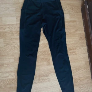 Svarta leggings med fickor - Svarta leggings med hög midja och praktiska sidofickor. Tight passform och stretchigt material och mesh på sidorna 