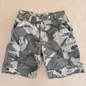 VINTAGE Wrangler-shorts - Coola vintage cargoshorts i militärstil från Wrangler 💚 Välbevarade, i mycket fint skick! Köpta från Beyond Retro för några år sedan, sparsamt använda sedan dess. 100% bomull. Midja: 41x2 cm. Längd: 54 cm. (Motsvarar herr strl. M, dam storlek L eller mindre om man vill ha dem oversized :). Pris är självklart förhandlingsbart 💕 Hör gärna av er vid frågor och glöm inte att kolla in garderoben för fler liknande plagg!