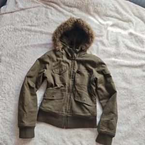 Olivgrön jacka med fuskpäls från Only - Only jacka köpt på vinted<3 säljer då jag rensar garderoben!! Kedjan har vart krånglig ibland men den har funkat.