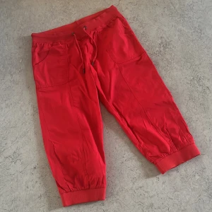 Röda croppade mjukisbyxor med snörning - Snygga röda mjukisbyxor med croppad längd och resår i midjan samt benslut. Byxorna har snörning i midjan och praktiska fickor framtill. Perfekta för en chill och avslappnad stil.